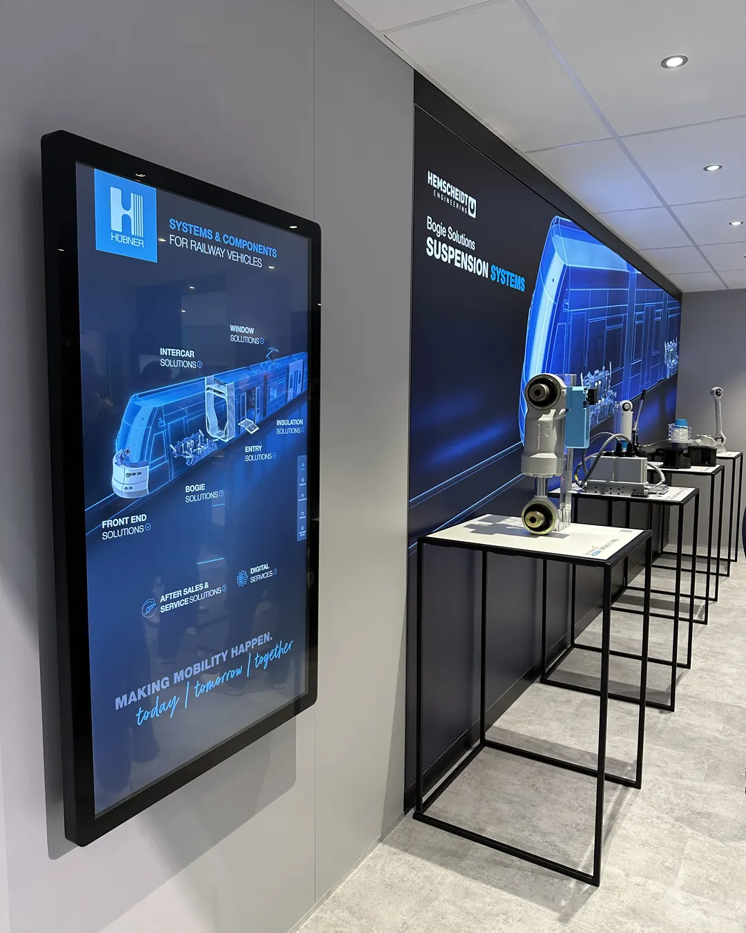 HÜBNER Group - InnoTrans 2024: Wall-Mounted Display Next to the HEMSCHEIDT Bogie Solutions